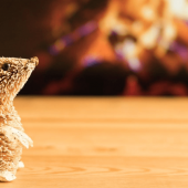 A small wicker mouse in front of a fireplace.