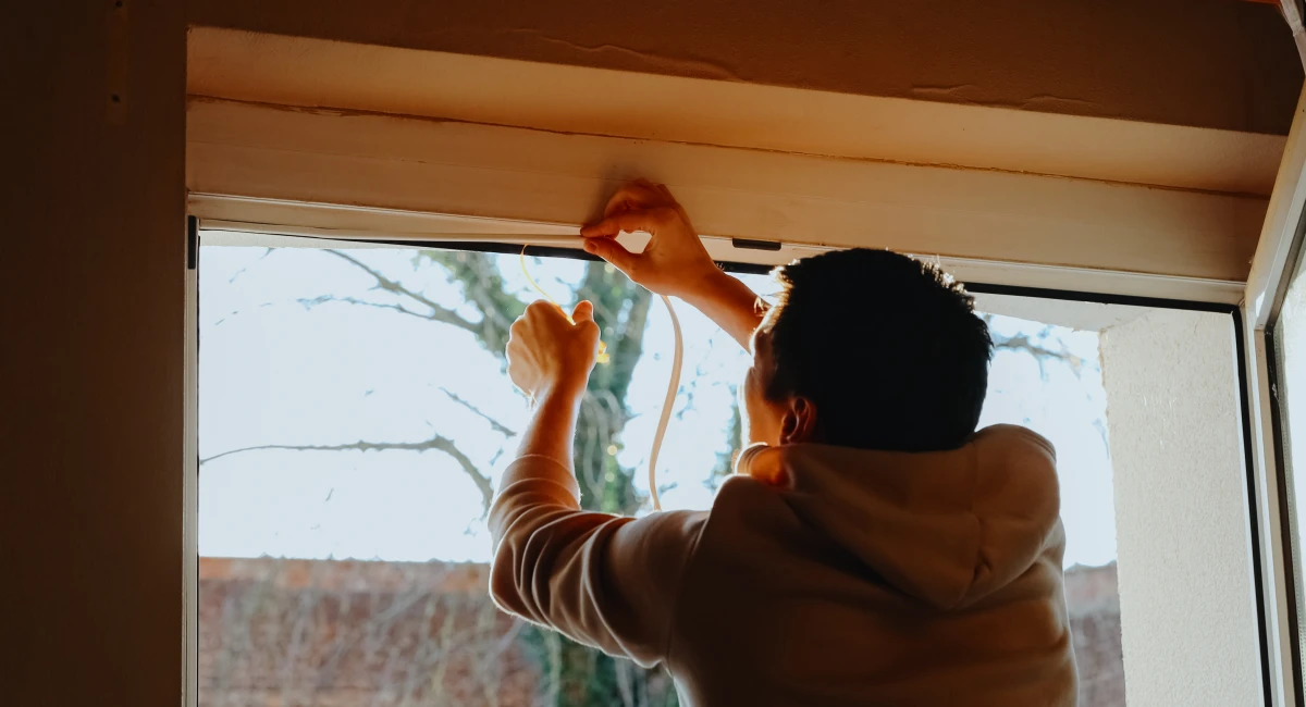 Worker applies sealant foam to window frames, sealing gaps for insulation during home improvement effort.