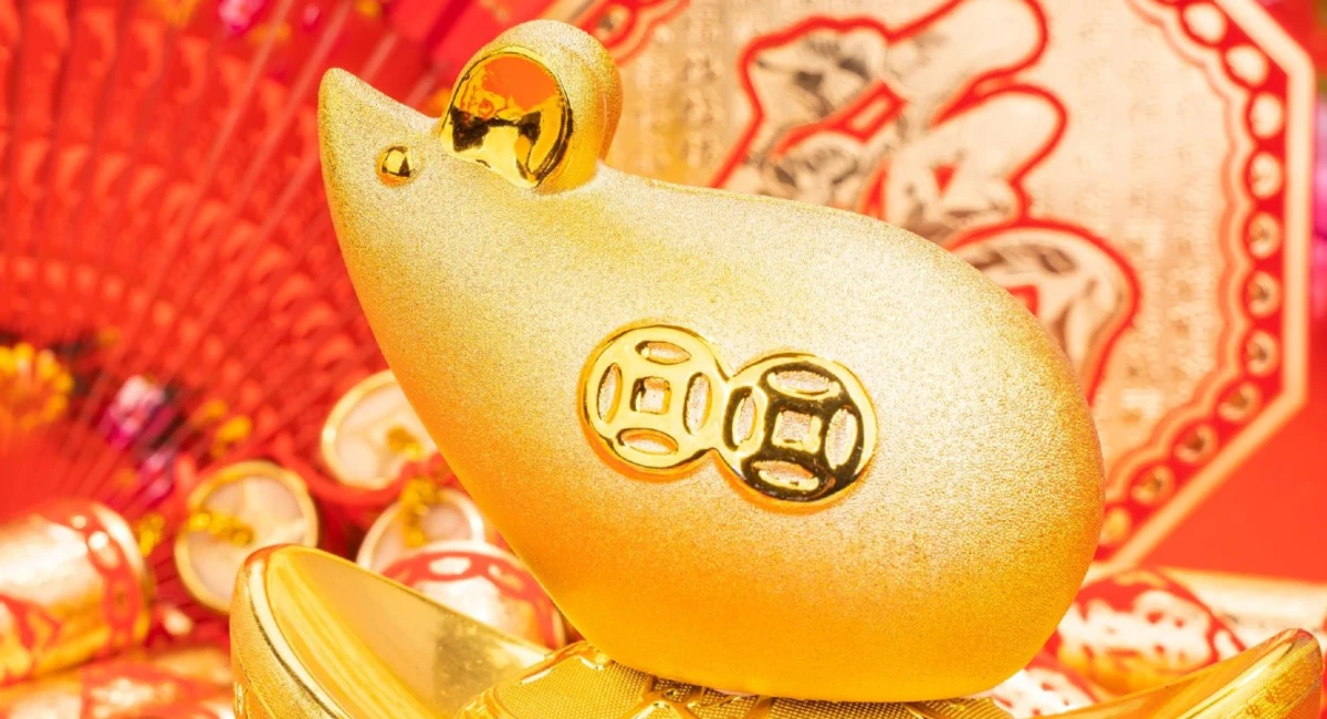 Gold figurine of a rat among red and gold chinese new year decorations 