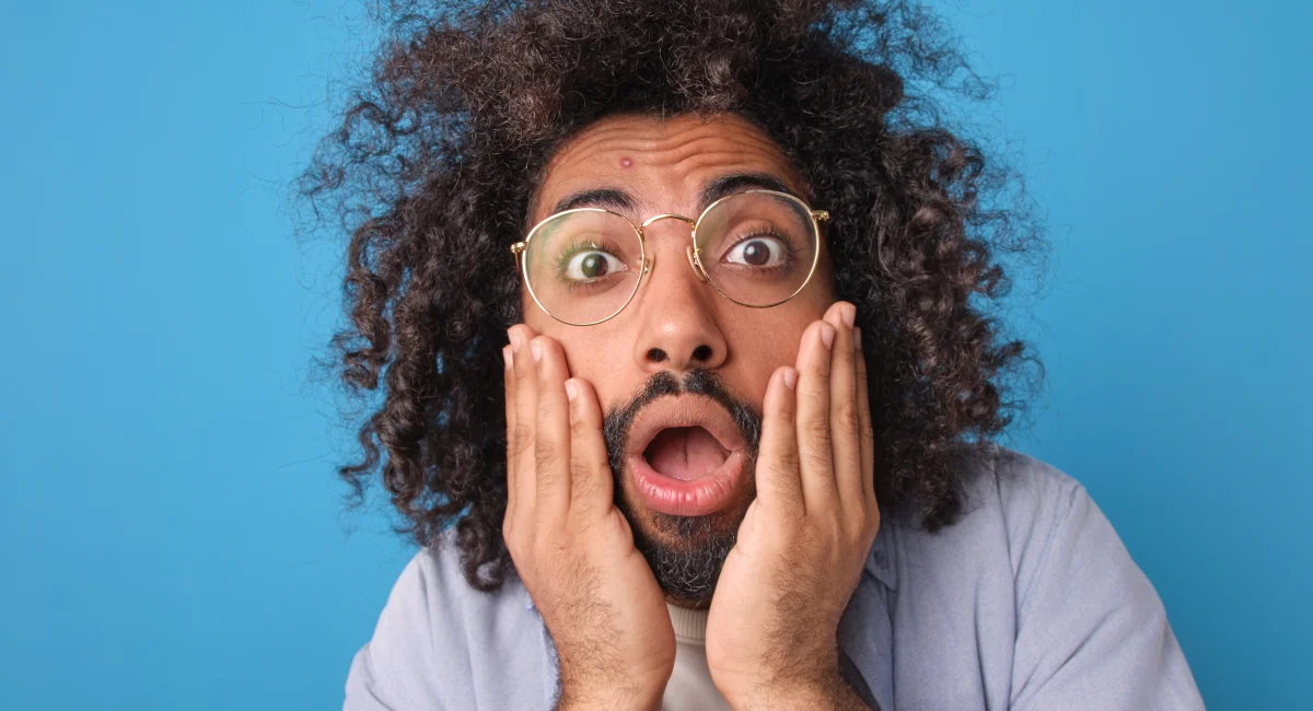 Young man with hands on face shocked