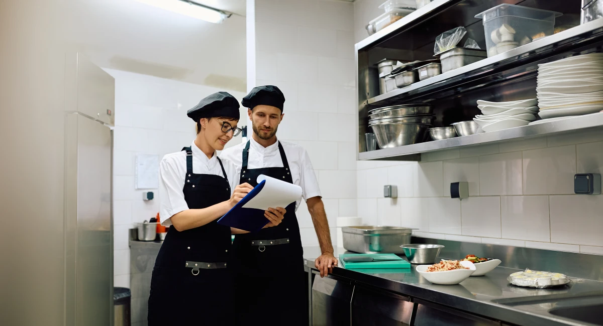 Restaurant cooks cooperating while going through check list in the kitchen
