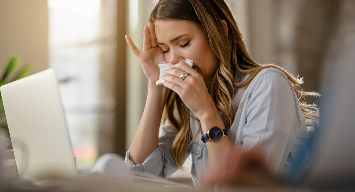 woman with cold wiping nose 