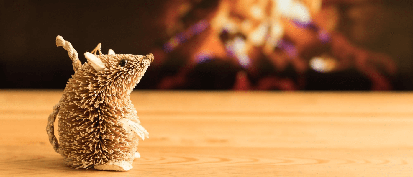 A small wicker mouse in front of a fireplace.