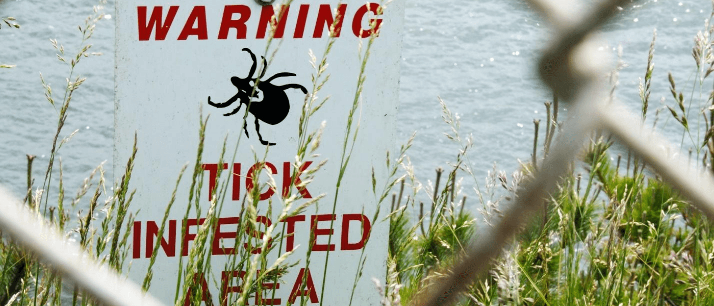 A sign warning of ticks in tall grass.