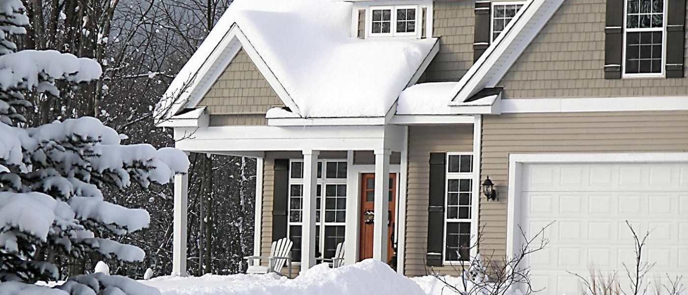 A home covered by snow and surrounded by trees