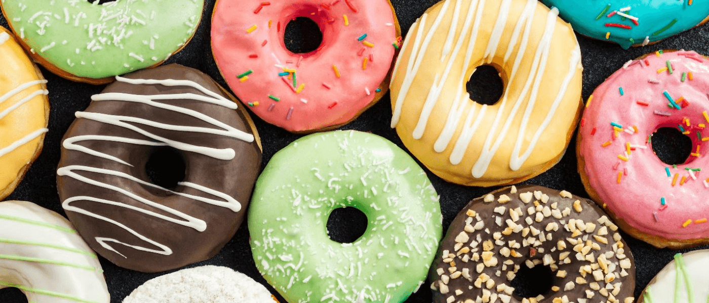 A lineup of freshly-baled donuts with colorful frosting.