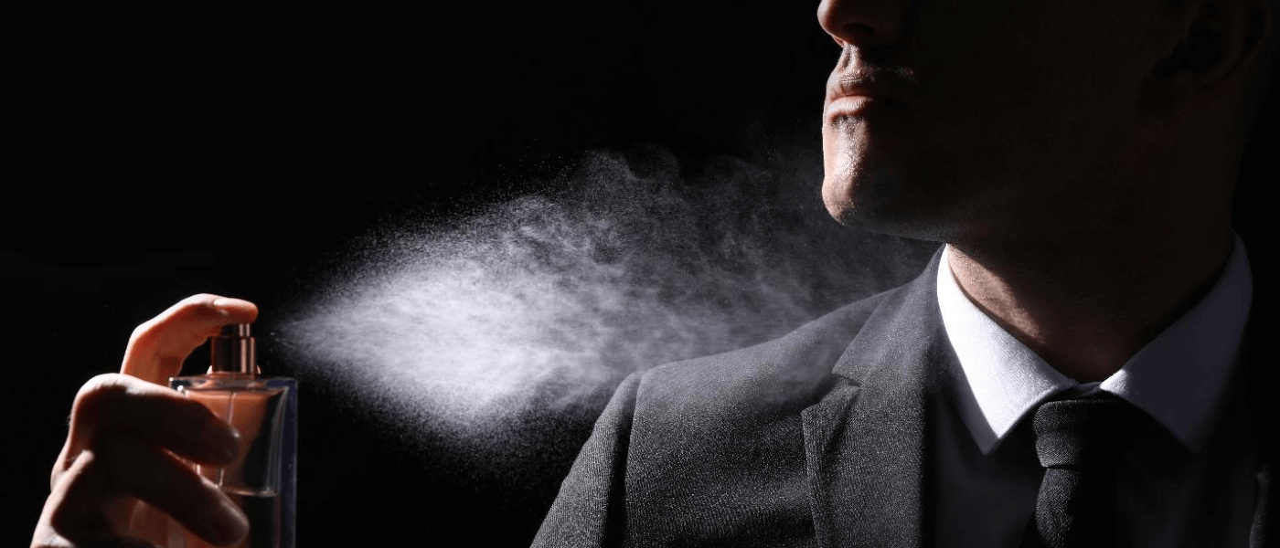 A man spraying himself with cologne.