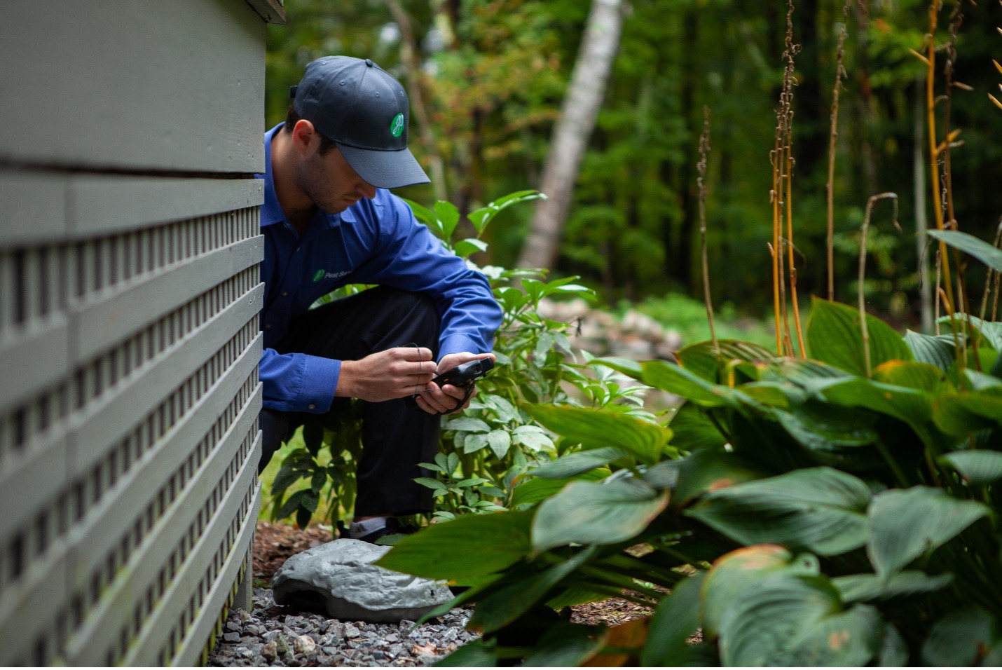 JP Pest Services technician inspecting the exterior of a multifamily property during a routine pest control check in New England.