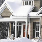 A home covered by snow and surrounded by trees