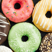 A lineup of freshly-baled donuts with colorful frosting.