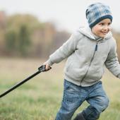 Boy pulls a red wagon with pumpkins across a field