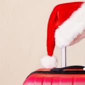 A Santa hat and miniature airplane resting on top of a red suitcase