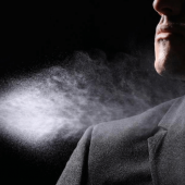 A man spraying himself with cologne.