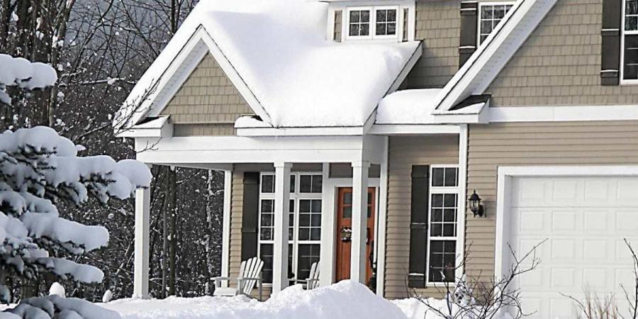 A home covered by snow and surrounded by trees