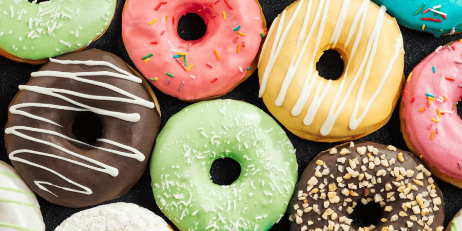 A lineup of freshly-baled donuts with colorful frosting.