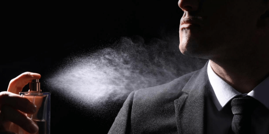 A man spraying himself with cologne.