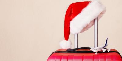 A Santa hat and miniature airplane resting on top of a red suitcase